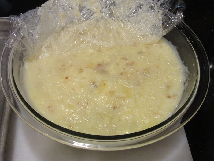 Plastic wrap being removed from a set custard for making banana cream pie.