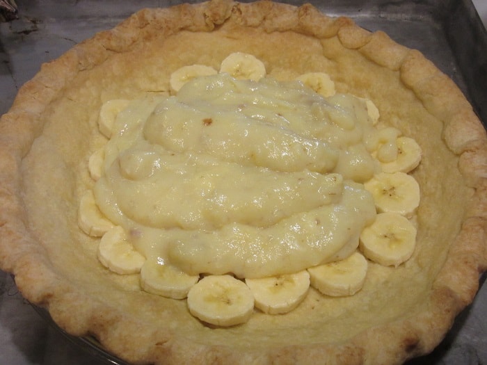 Banana custard poured over sliced bananas in a pie.