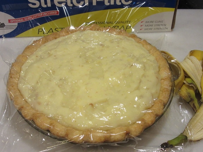 Plastic wrap covering the custard of a banana cream pie before the whipped cream topping.