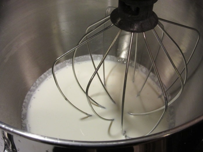 Heavy cream in a stand mixer with the whip attachment.