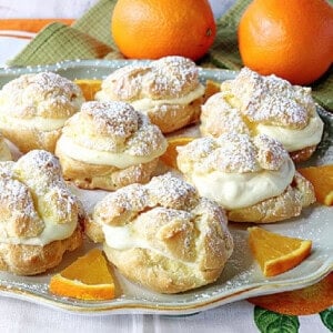 Pretty Orange Cream Eclairs on a platter with fresh orange slices.