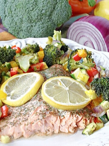 Roasted Rainbow Trout on a plate with lemon slices.
