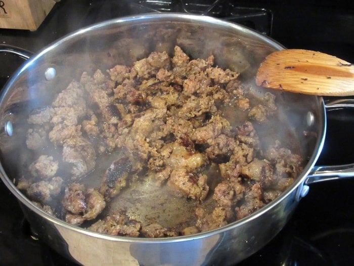 A large skillet with browned ground sausage.