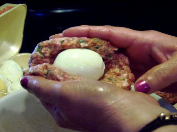 Wrapping sausage around an egg to make Scotch Eggs.