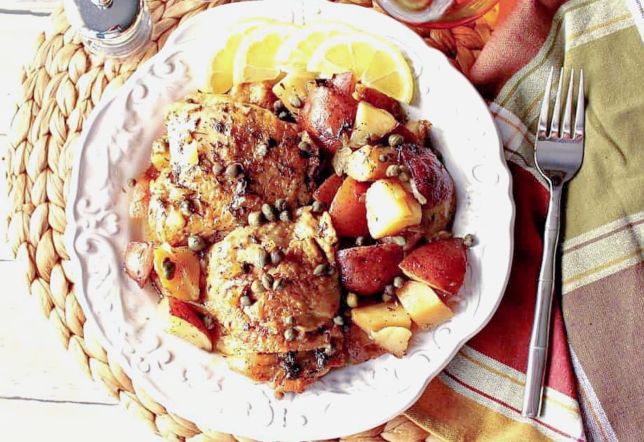 A direct overhead photo of Chicken Vesuvio made in a slow cooker on a white plate with a fork and a colorful napkin.