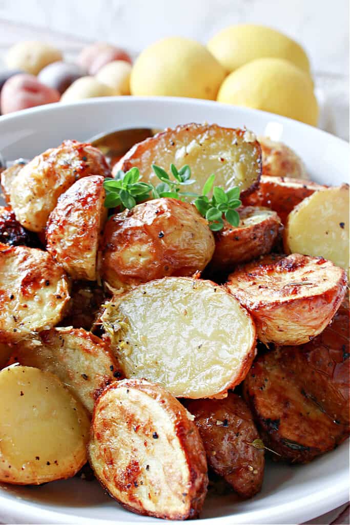 Super closeup vertical photo of golden and crispy Air Fryer Baby Potatoes along with some fresh thyme as garnish.