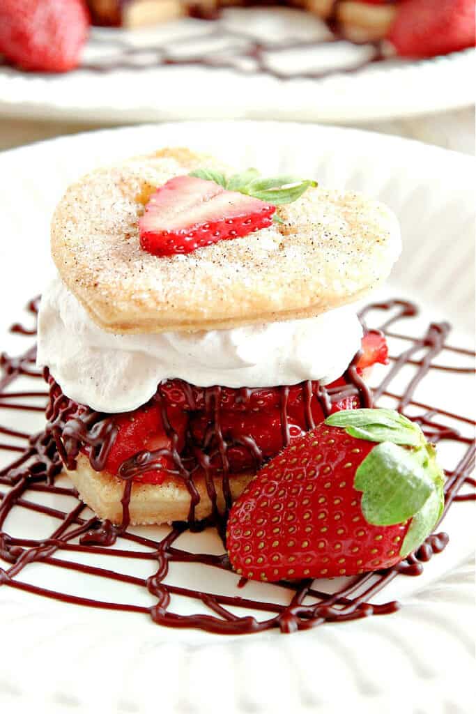 A closeup vertical image of a Deconstructed Strawberry Pie with cinnamon sugar pie crust hearts, strawberries, and chocolate ganache.