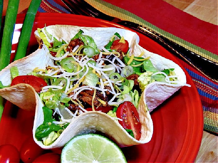 A Lighter Taco Salad on a red plate with cheese and scallions.