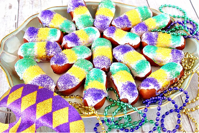 A platter filled with Mini Long Johns along with mardi gras beads and a mask.