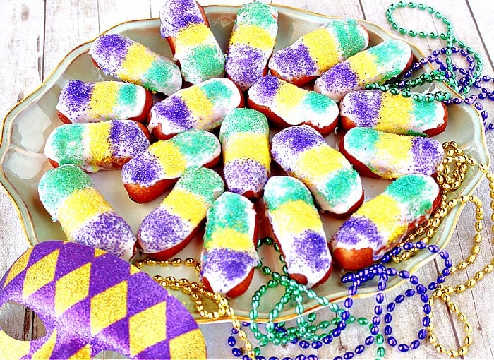 A platter filled with Mini Long Johns that have been decorated for Mardi Gras with green, yellow, and purple sanding sugar.