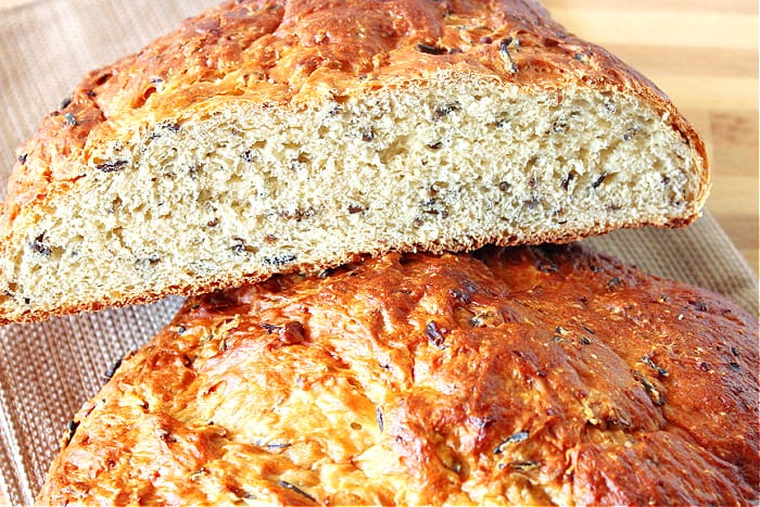 A closeup horizontal photo of a slice of Wild Rice Bread with onions with a golden crust.