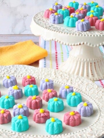 A pretty white plate and cake stand filled with pastel colored Buttermint Candy Flowers.