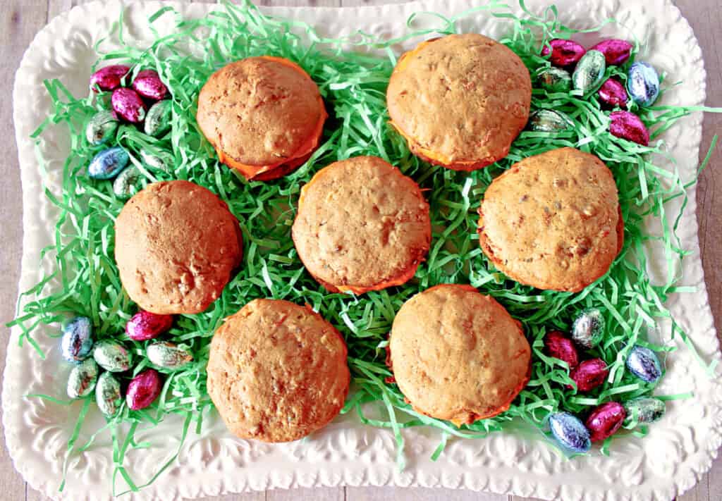 A directly overhead photo of a platter of Carrot Cake Whoopie Pies with green Easter grass and foil covered chocolate eggs.