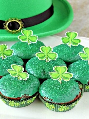 Cute green chocolate mint brownie cupcakes on a plate with shamrocks on top.