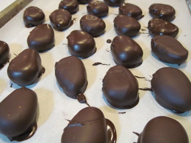 Chocolate dipped peanut butter eggs on parchment paper.