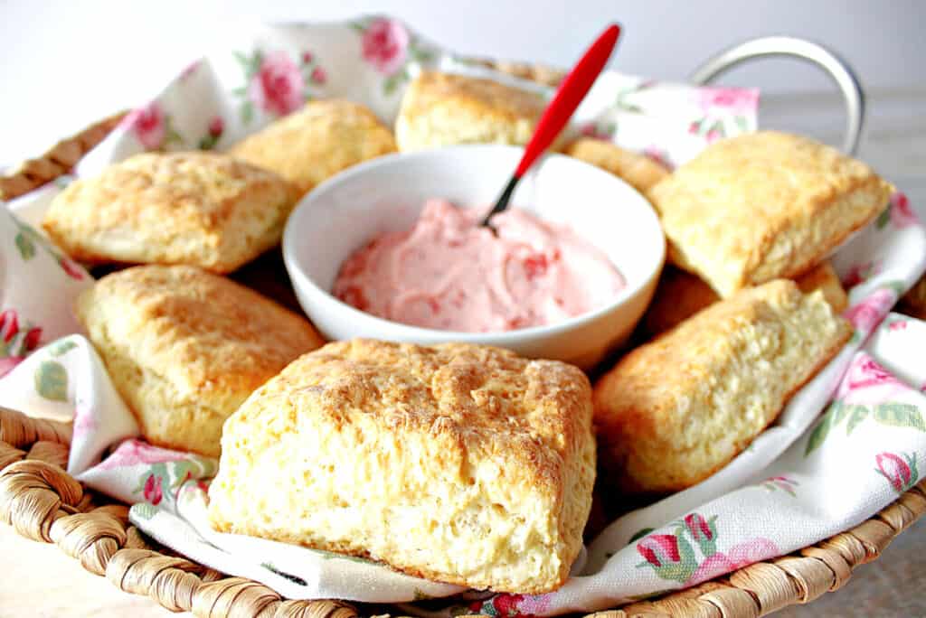 A pretty basket with a pink rose napkin filled with Cream Cheese Biscuits with Strawberry Butter in the center.