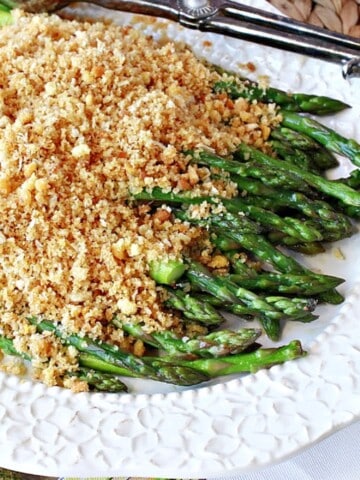 A pretty white platter filled with Grandma's Asparagus with Breadcrumbs.