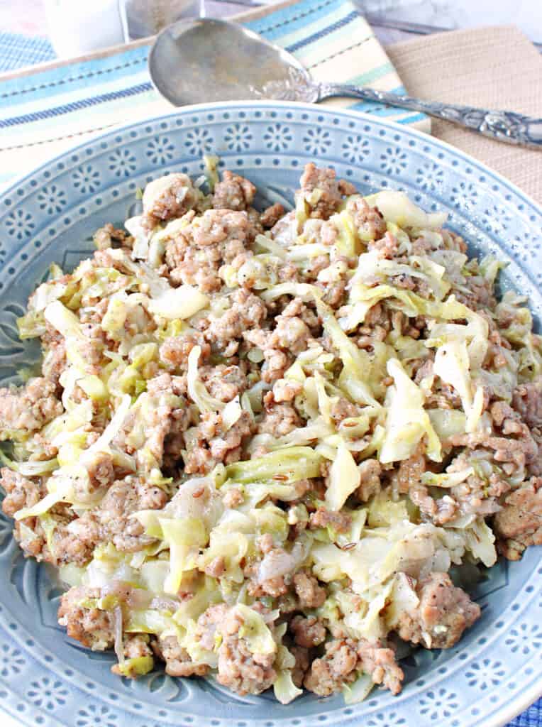 A vertical overhead closeup of a recipe for Ground Pork and Cabbage Skillet in a pretty blue bowl.