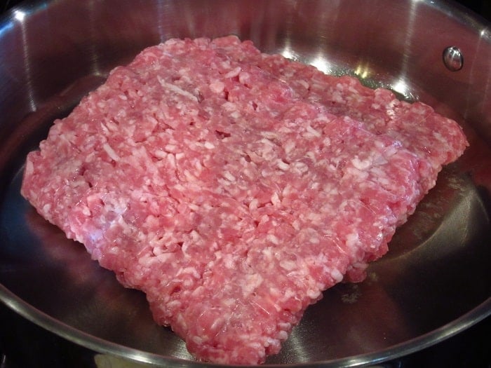 Uncooked ground pork in a skillet.