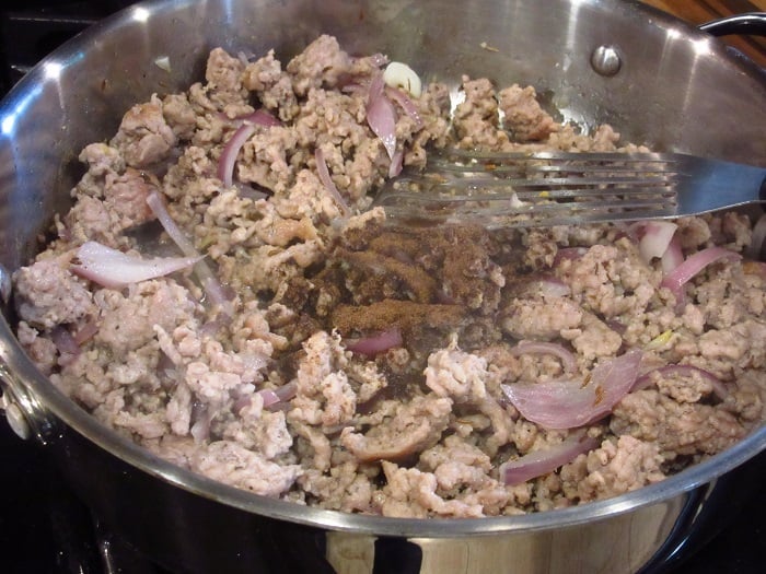 Ground pork browning in a skillet along with allspice.