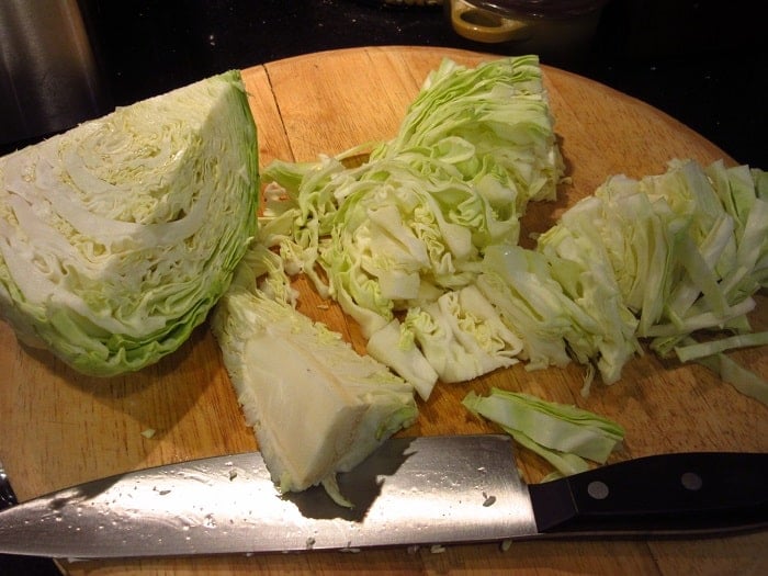 Fresh sliced cabbage on a wooden cutting board.