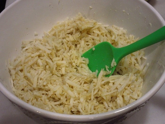 Thawed hash brown potatoes in a bowl with a spatula.