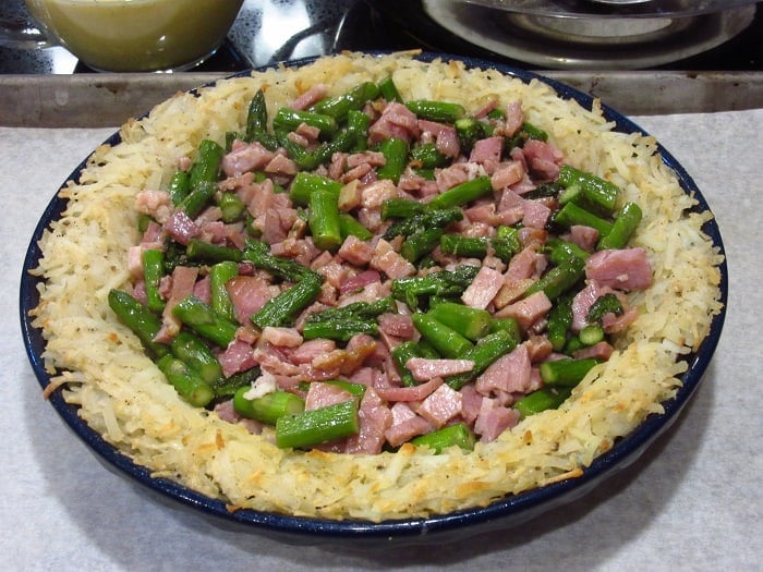 A quiche loaded with ham and asparagus before baking.