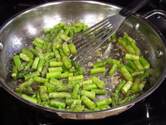 Seasoned asparagus pieces in a skillet.