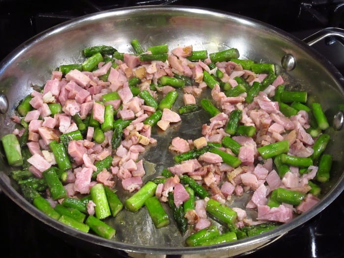Ham and asparagus in a skillet on the stovetop.