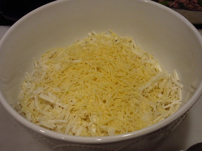Frozen hash brown potatoes in a bowl with cheese.