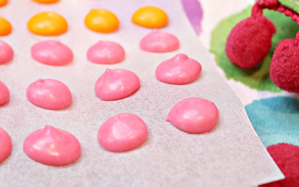 A super closeup horizontal image of pink Homemade Candy Dots on a strip of white parchment paper.