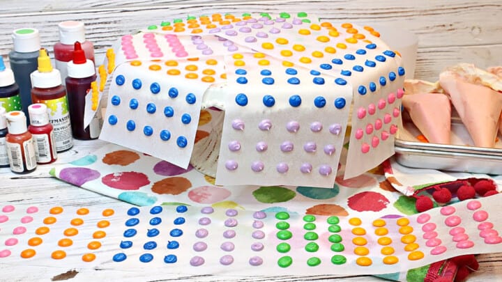 A cake plate and table filled with colorful Homemade Candy Dots on paper strips.