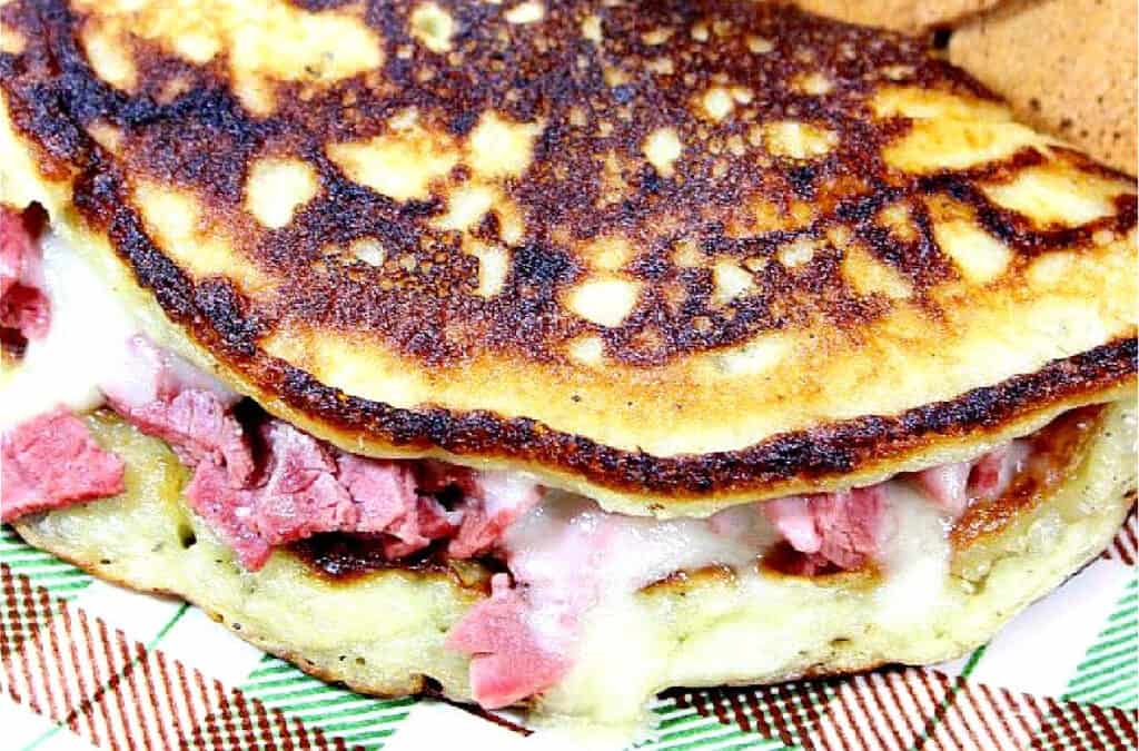 A super closeup horizontal photo of an Irish Corned Beef Boxty stuffed with chopped corned beef, and melted Swiss cheese in a golden brown potato pancake.
