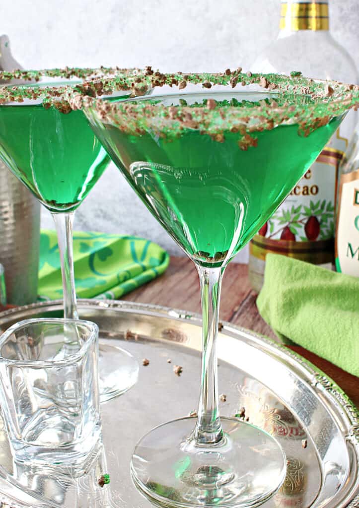 A close vertical image of two green Irish Grasshopper Cocktails on a silver platter.