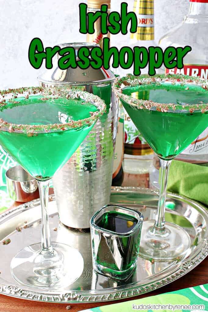 A vertical title text overlay graphic image of two bright green Irish Grasshopper Cocktails along with bottles of alcohol in the background.