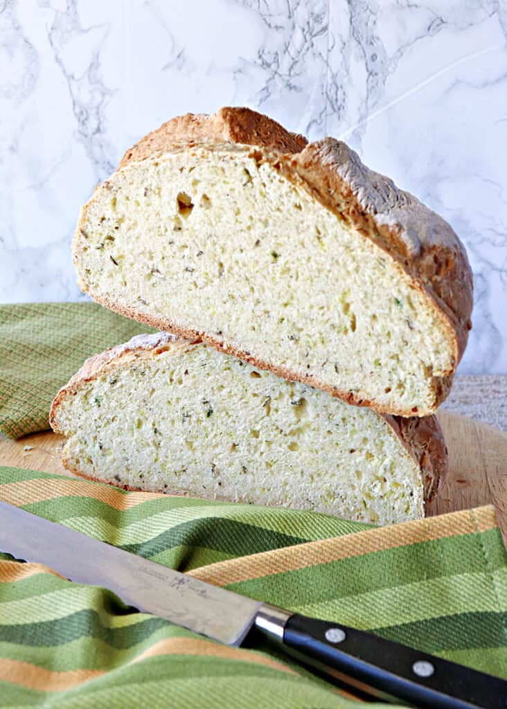 A vertical image of an Irish Soda Bread with Caraway and Dill that's been cut in half with the two halves stacked on top of each other.