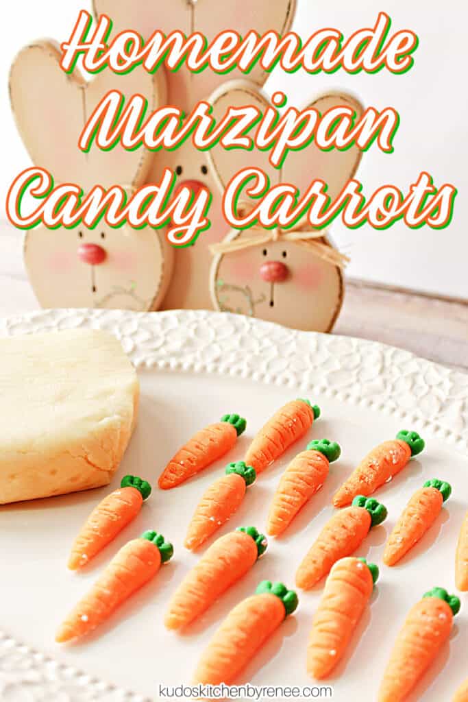 A vertical closeup image of a bunch of Homemade Marzipan Candy Carrots on a platter with a block of homemade marzipan in the background.