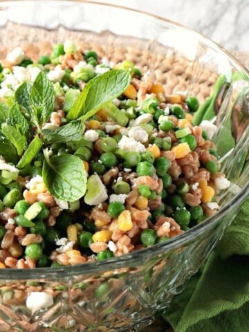 A Farro Salad with Peas in a glass bowl topped with mint.