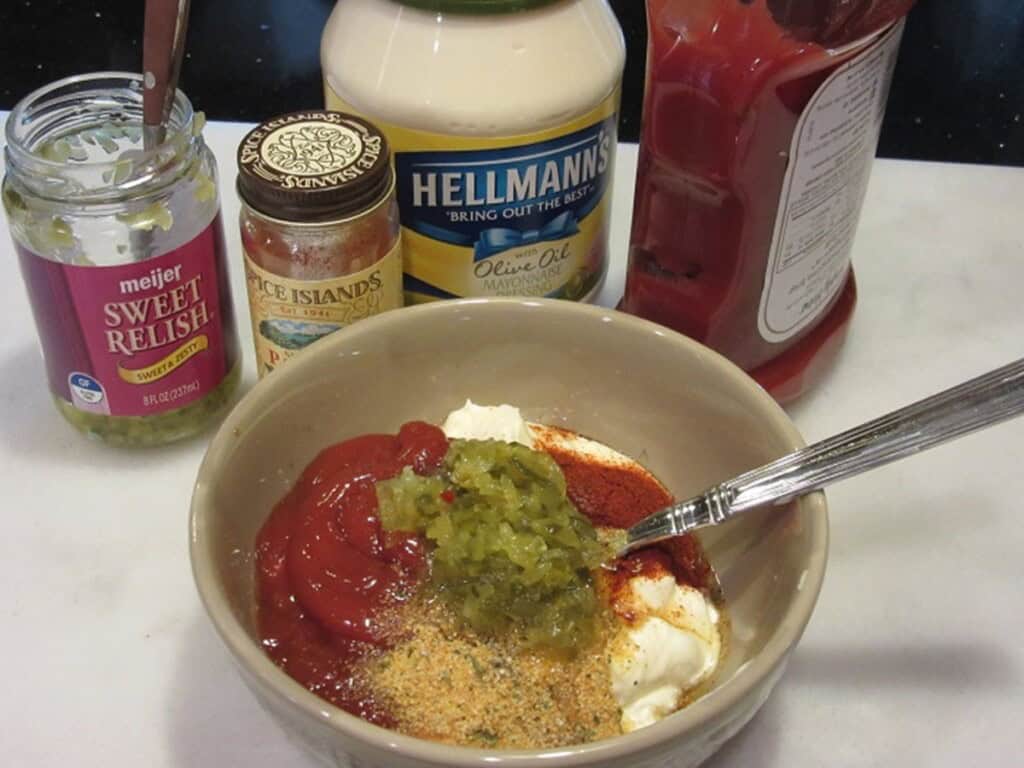 The ingredients for making a homemade thousand islands sauce in a bowl with a spoon.