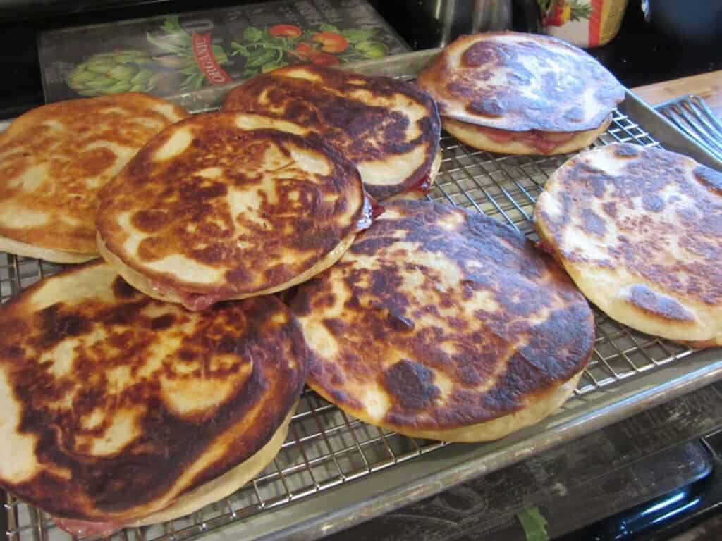 A bunch of golden brown Reuben quesadillas on a rack ready to be warmed in the oven.