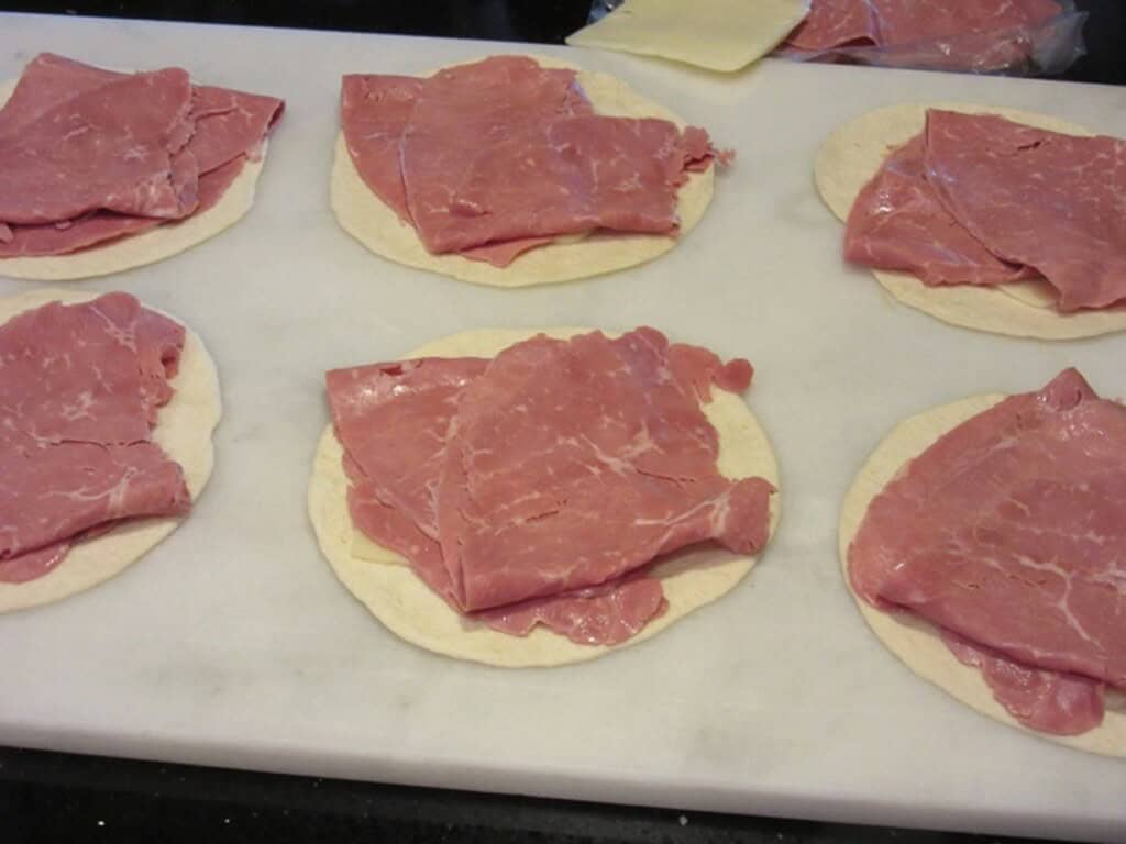 Sliced corned beef on top of flour tortillas for making quesadillas.