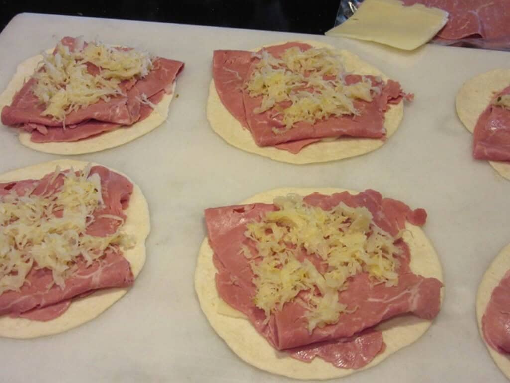 Flour tortillas, corned beef, and sauerkraut on a marble countertop.