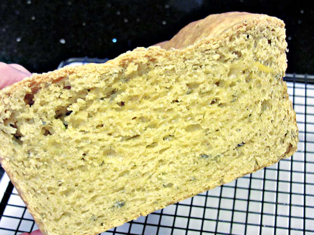 A closeup photo of a slice of Avocado Yeast Bread with flecks of cilantro on the inside. 