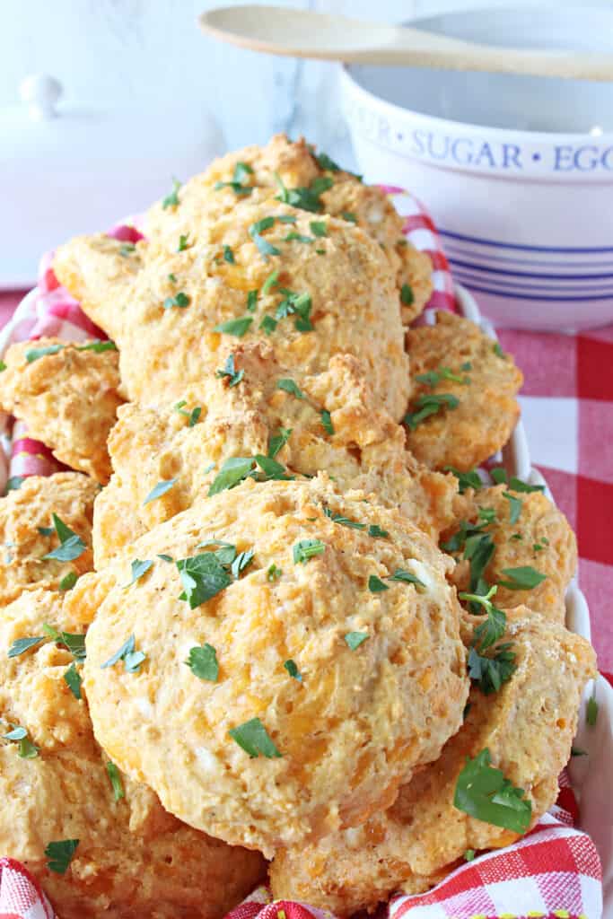 A vertical closeup of a basket of Better Cheddar Bay Biscuits topped with parsley.