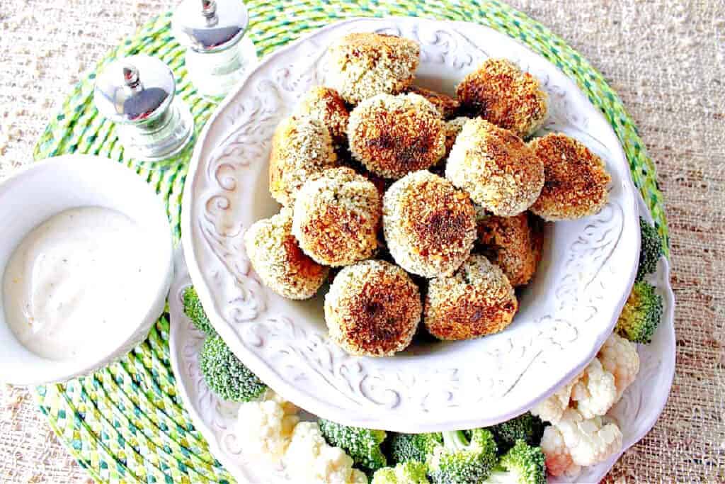 An overhead horizontal photo of a white bowl filled with Broccoli Cauliflower Vegetable Tots along with fresh broccoli and cauliflower as garnish.