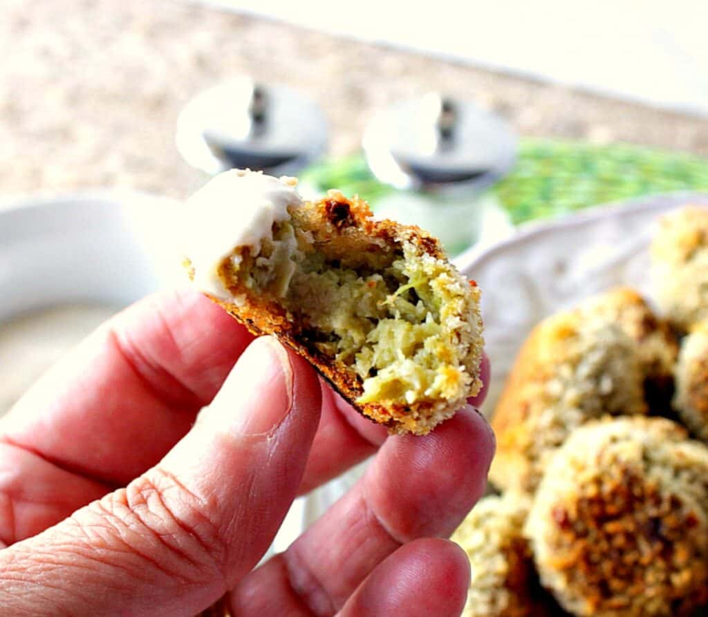 A hand holding a Broccoli Cauliflower Vegetable Tot with a bite taken out.