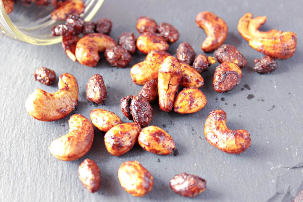 Brown Butter Roasted Nuts with cashews, almonds, and pistachios spilled out on a slate tile.