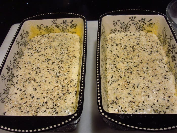 Two loaves of Everything Bagel English Muffin Bread topped with everything seasoning before baking.