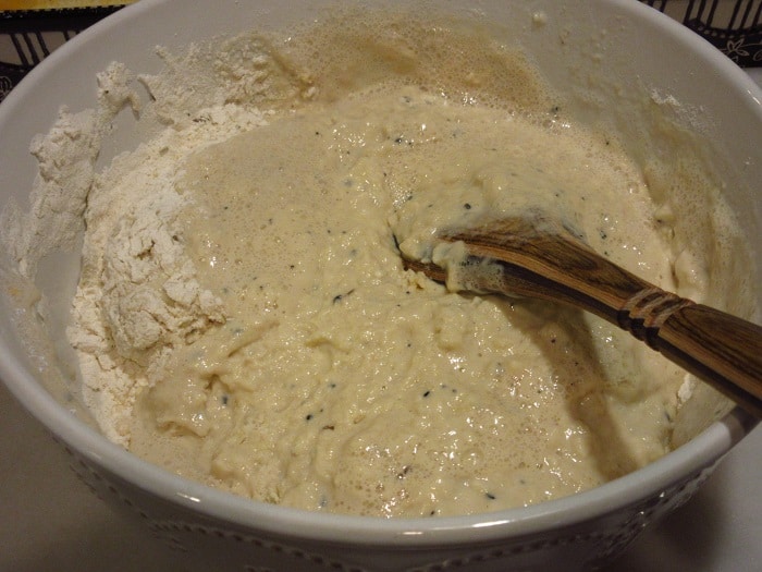 A wooden spoon mixing a bowl of dough.