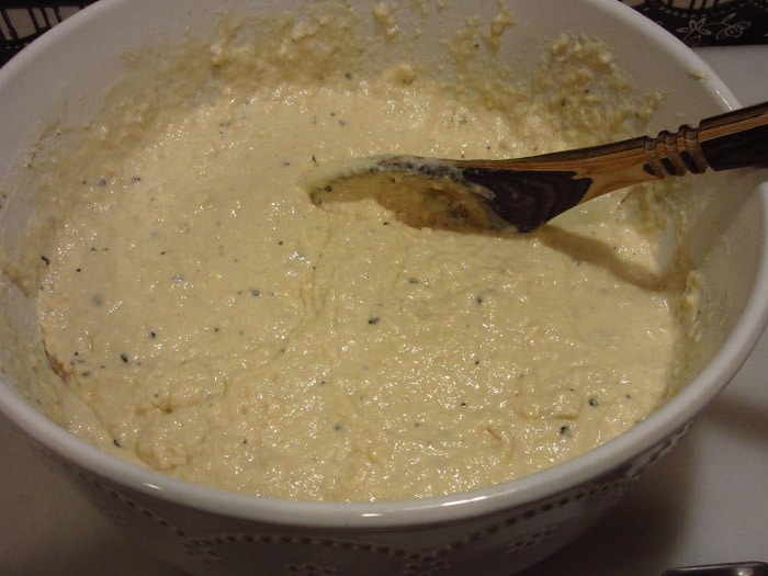 A wooden spoon mixing a bowl of dough.